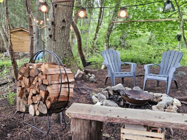 Two chairs and benches surrounded by a fire pit. 